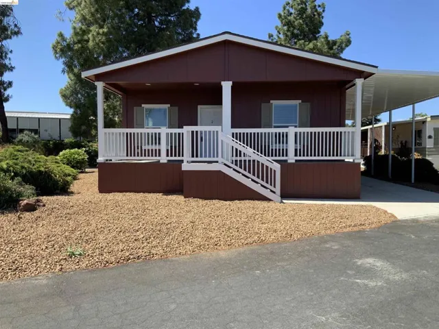 Manufactured / mobile home with a porch, a carport, and driveway