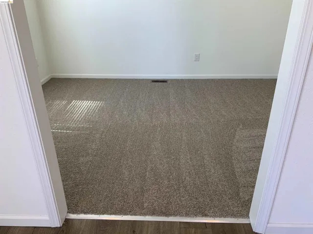 Unfurnished room with baseboards and dark carpet