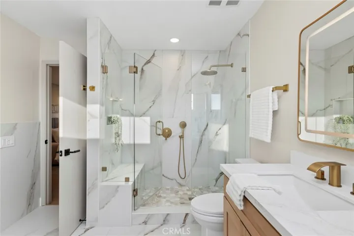custom frameless glass shower with rainfall showerhead, oversized niche, and built-in bench