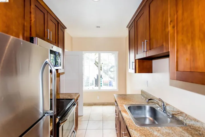 Kitchen featuring stainless steel appliances, wood finish cabinets, light countertops, and light tile patterned floors