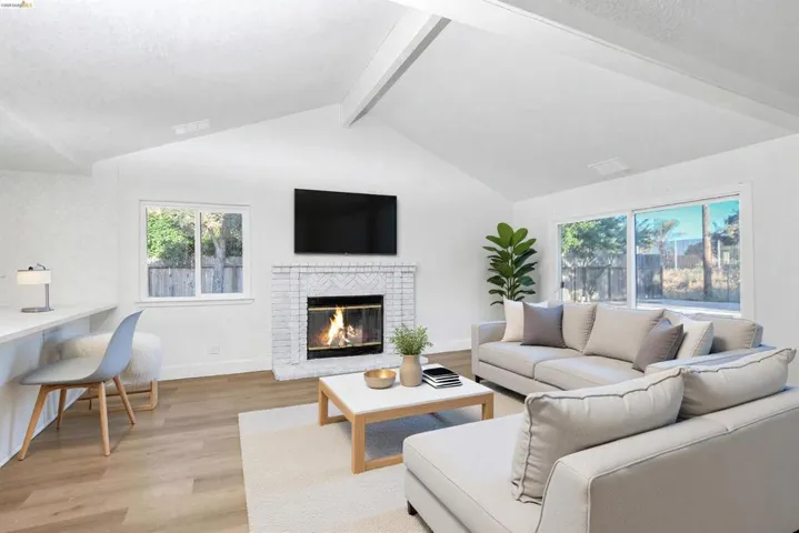 Living room featuring light wood-type flooring, a fireplace, and beamed ceiling