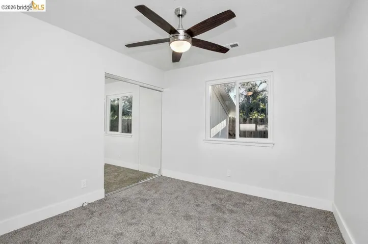 Carpeted spare room with healthy amount of natural light and a ceiling fan