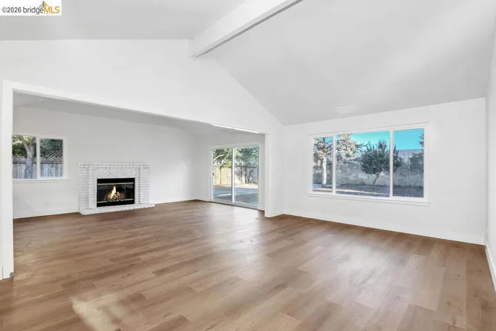 Unfurnished living room featuring dark wood finished floors and a brick fireplace