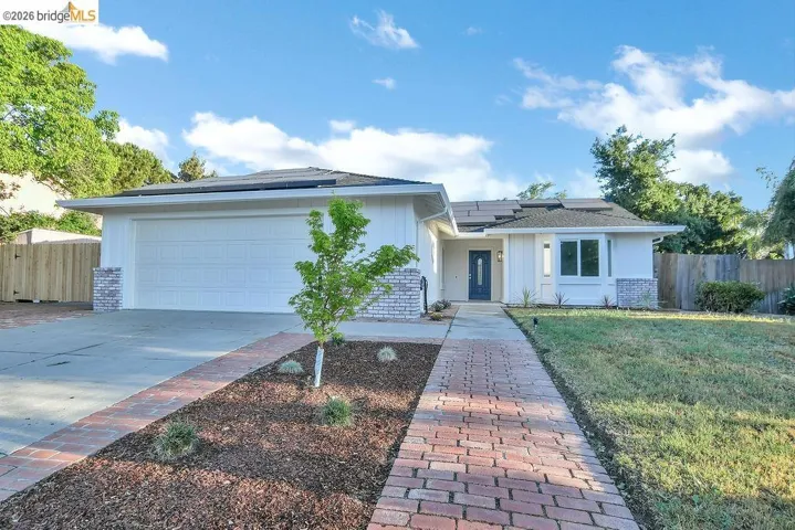 Ranch-style house featuring roof mounted solar panels, driveway, a garage, and brick siding