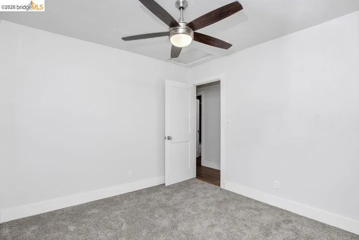 Empty room with carpet flooring and a ceiling fan