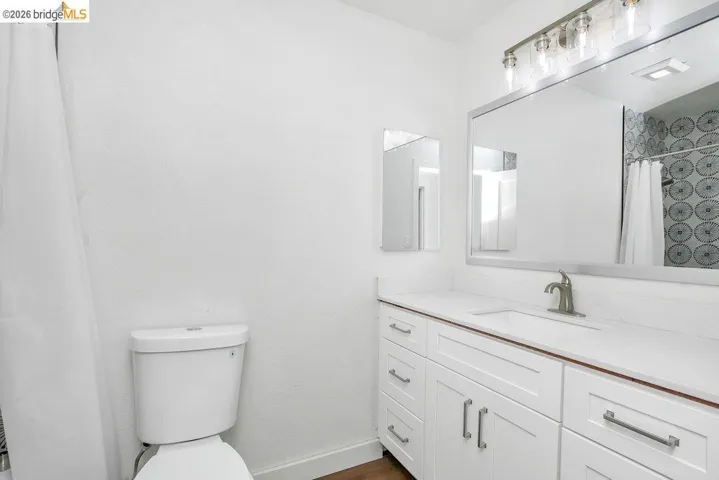 Full bathroom featuring a shower with shower curtain, vanity, and dark wood-style floors