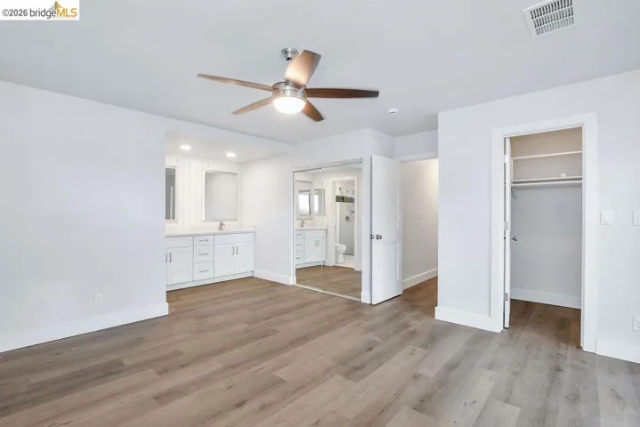 Unfurnished bedroom with ensuite bathroom, dark wood-style flooring, a ceiling fan, and recessed lighting