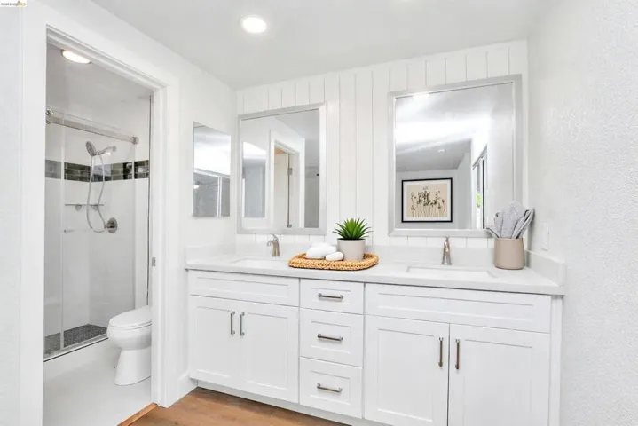 Bathroom featuring double vanity, a shower stall, light wood finished floors, and recessed lighting