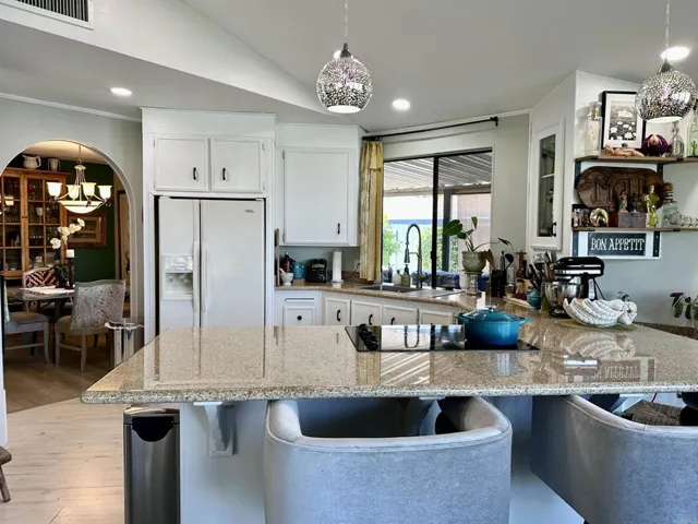 Dynamic angle kitchen with additional shelves above a bar sink area, & arch door to formal Dining.