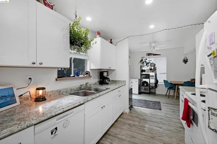 Kitchen with white appliances, white cabinets, plenty of natural light, light wood-style floors, and recessed lighting
