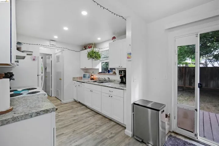 Kitchen with white cabinetry, light countertops, recessed lighting, white appliances, and light wood-type flooring