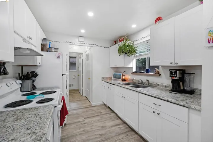 Kitchen featuring white appliances, white cabinetry, light wood finished floors, and recessed lighting