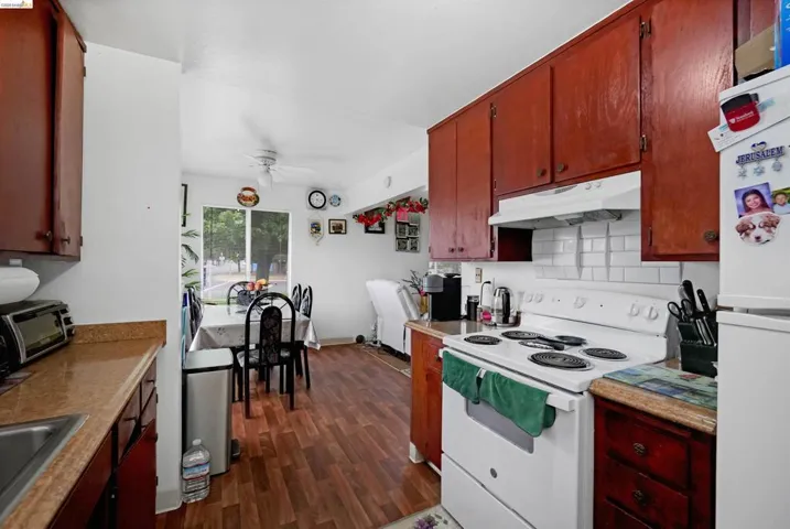 Kitchen with white appliances, backsplash, light countertops, dark wood-type flooring, and a ceiling fan
