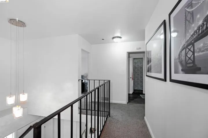 Hallway featuring an upstairs landing and light carpet