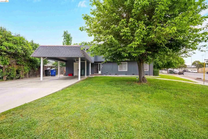 View of front of property with a carport, concrete driveway, mansard roof, and roof with shingles