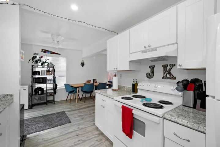 Kitchen with white appliances, white cabinetry, light countertops, and light wood finished floors