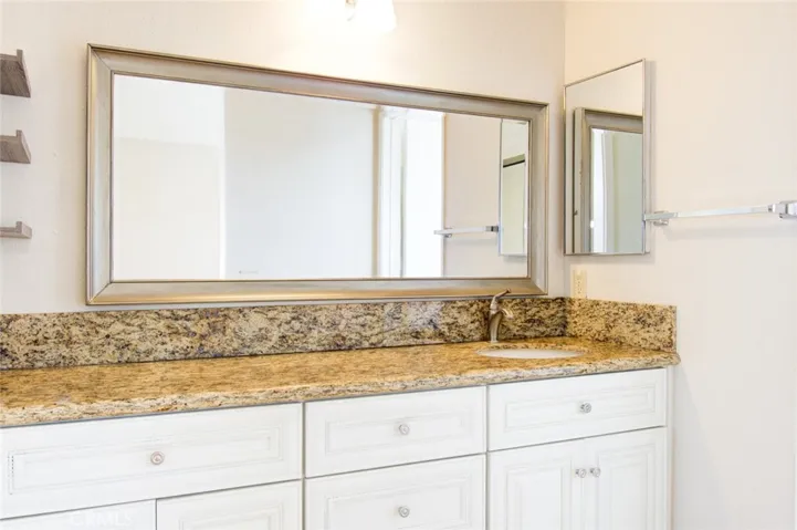The primary bathroom with granite countertop and white cabinets.