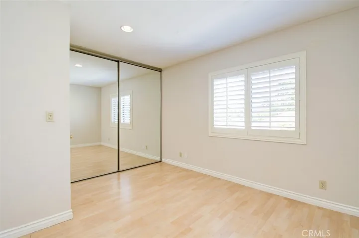 The third bedroom with mirrored closet door and wood shutters.