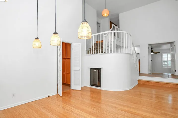 Unfurnished living room with a high ceiling, light wood finished floors, and a ceiling fan