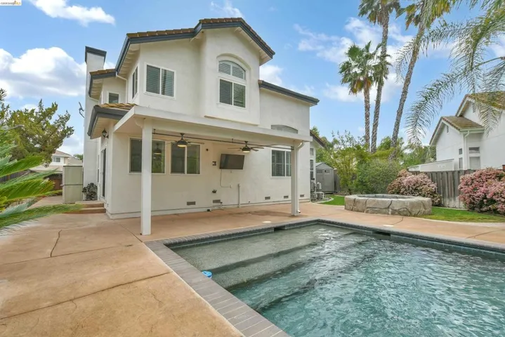 Back of house featuring a hot tub, a patio, a fenced backyard, a chimney, and ceiling fan