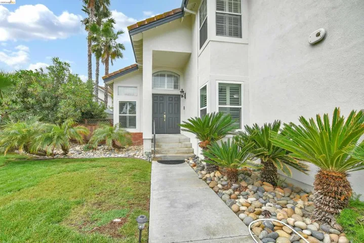 Entrance to property with stucco siding, a yard, and a tile roof
