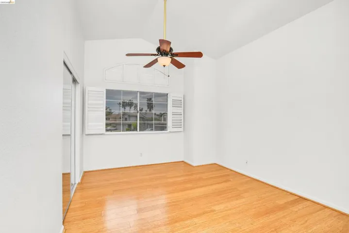 Empty room featuring lofted ceiling, ceiling fan, and light wood-type flooring