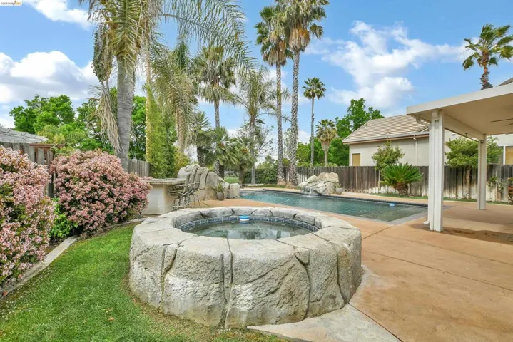 View of pool featuring patio surround, a fenced backyard, and an in-ground hot tub
