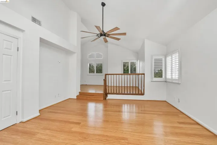 Unfurnished room with light wood-style floors, vaulted ceiling, and a ceiling fan