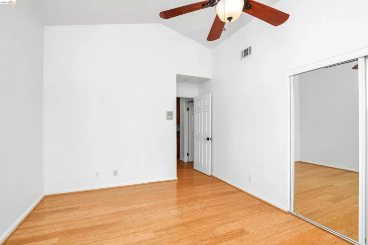 Unfurnished bedroom featuring light wood-style floors, a closet, ceiling fan, and lofted ceiling