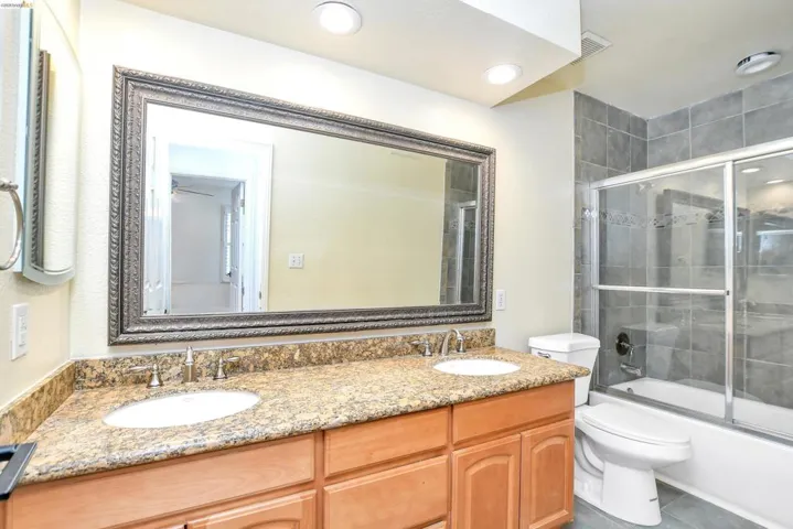 Full bath with double vanity and shower / bath combination with glass door