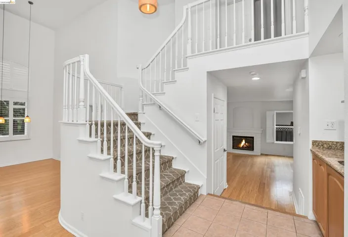 Staircase featuring a brick fireplace, tile patterned flooring, and a high ceiling