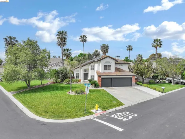 Mediterranean / spanish home featuring an attached garage, driveway, a front yard, brick siding, and stucco siding