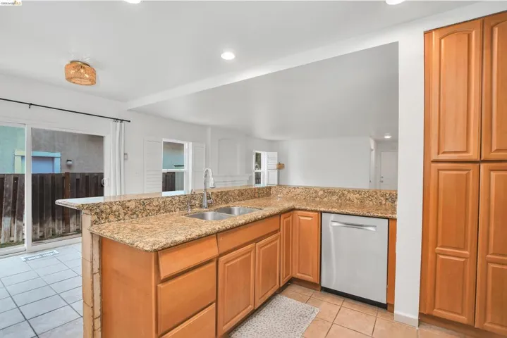 Kitchen featuring light stone counters, stainless steel dishwasher, light tile patterned floors, a peninsula, and recessed lighting