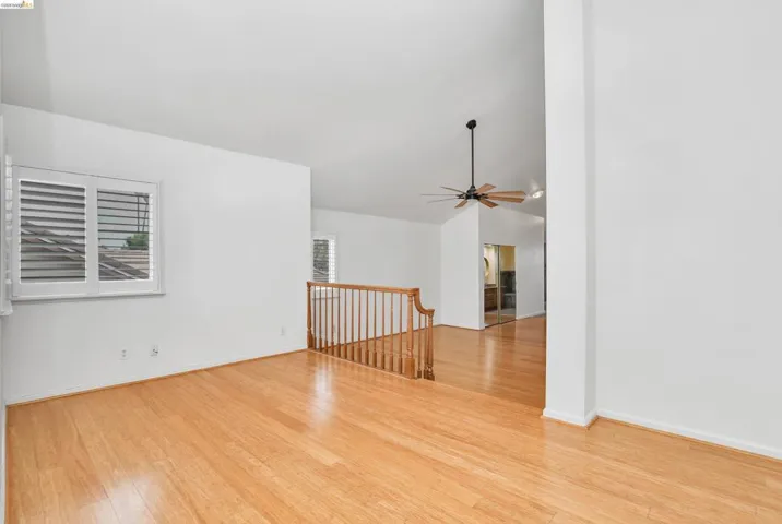 Empty room with light wood-type flooring, ceiling fan, and vaulted ceiling