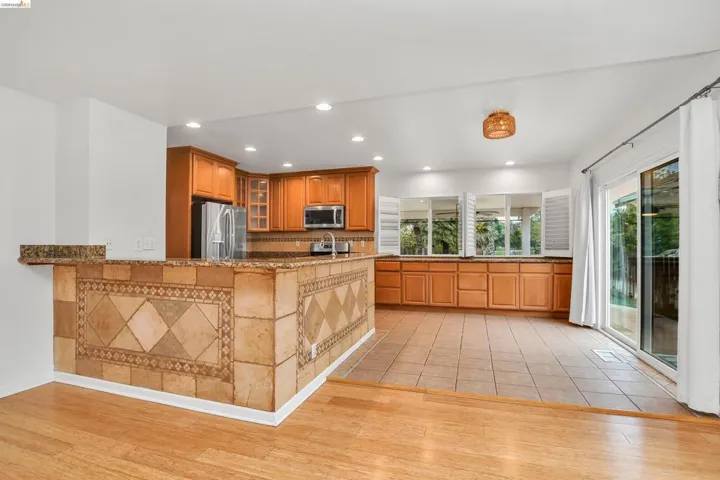 Kitchen featuring glass insert cabinets, wood finish cabinets, dark stone counters, recessed lighting, and stainless steel appliances