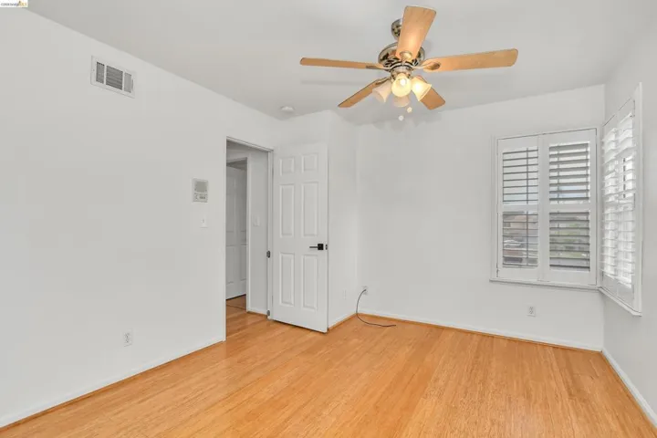 Empty room with a ceiling fan and light wood-type flooring