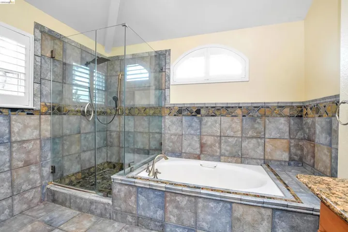 Bathroom featuring a stall shower, a garden tub, and vanity