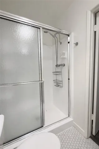 Bathroom with clean finishes, updated fixtures, and a glass-enclosed shower.