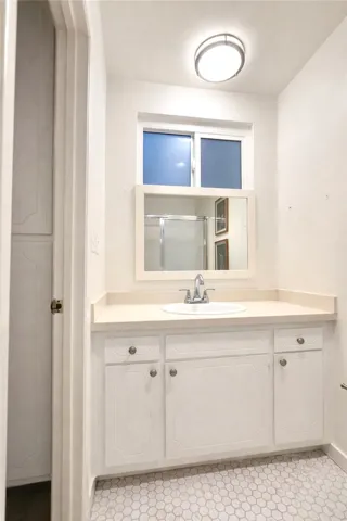 Bathroom featuring a clean vanity with ample counter space and integrated sink, offering both function and a streamlined look.