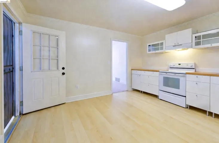 Kitchen featuring white cabinetry, white electric range, glass fronted cabinets, light countertops, and light wood-style floors