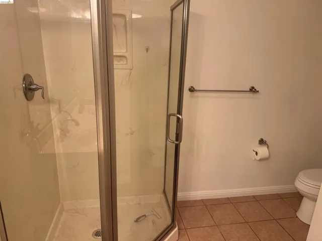 Bathroom featuring a marble finish shower and light tile patterned flooring