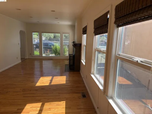Spare room with arched walkways, light wood-style floors, and ornamental molding