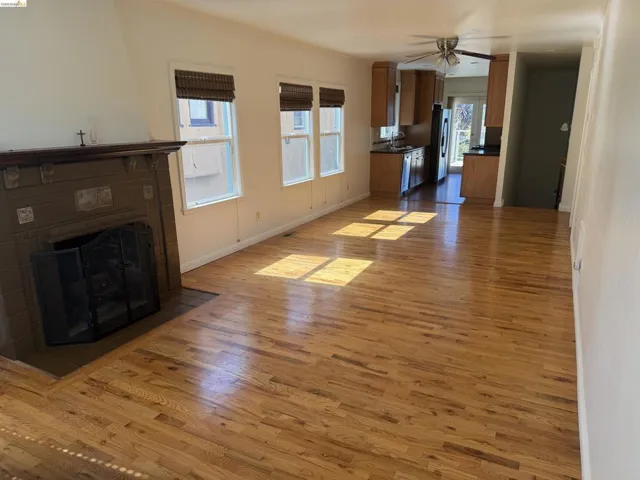 Unfurnished living room featuring light wood-style floors, a tile fireplace, and ceiling fan