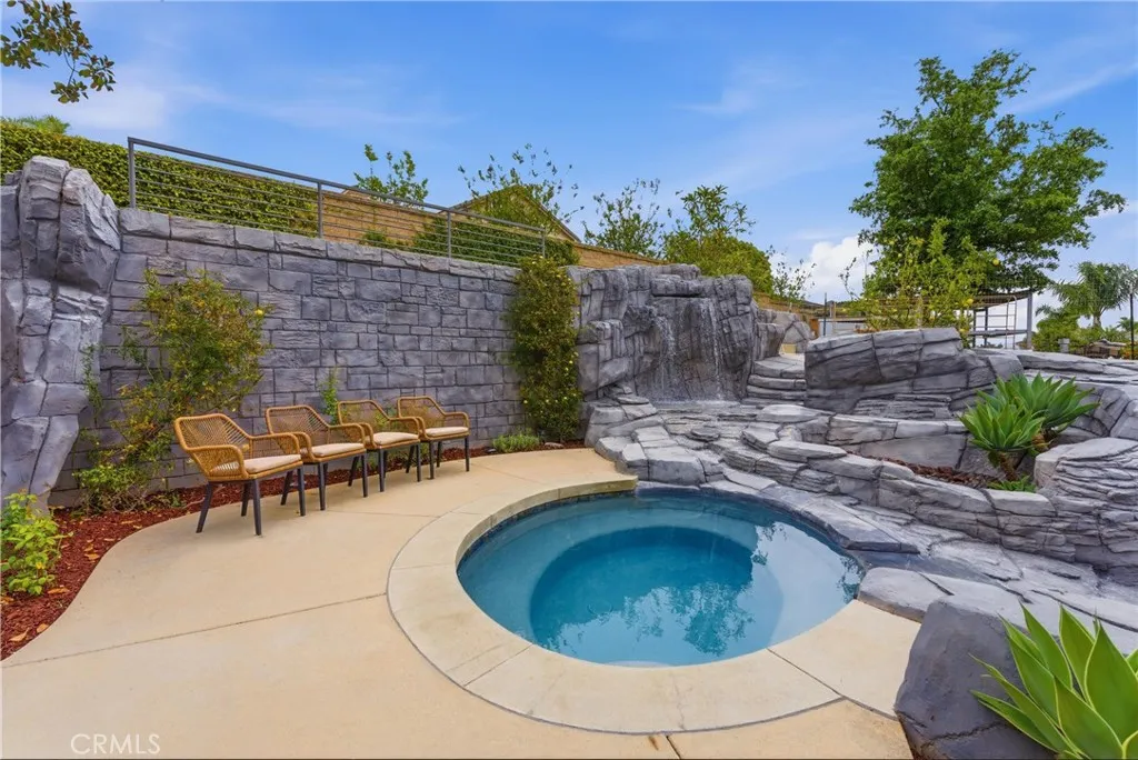 Rock spa and waterfall feature with stone landscaping with seating are