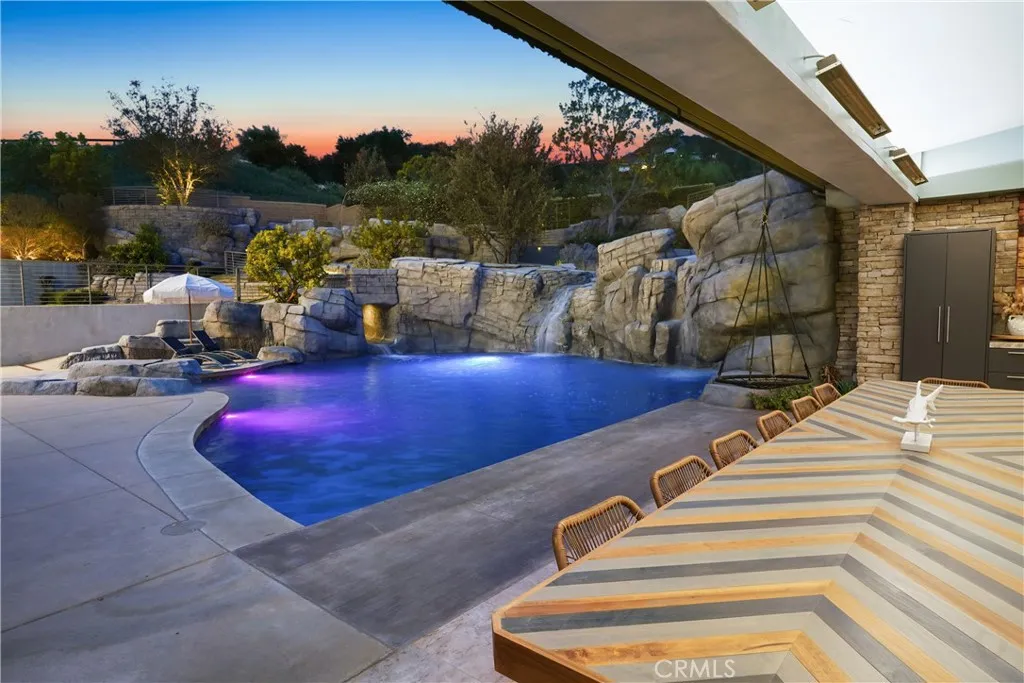 View of pool with waterfall from inside outdoor kitchen