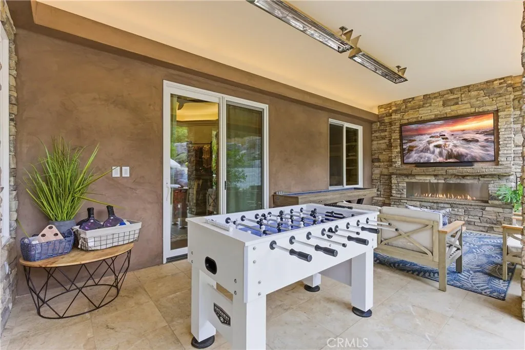 Outdoor lounge area with fireplace and TV entertainment wall