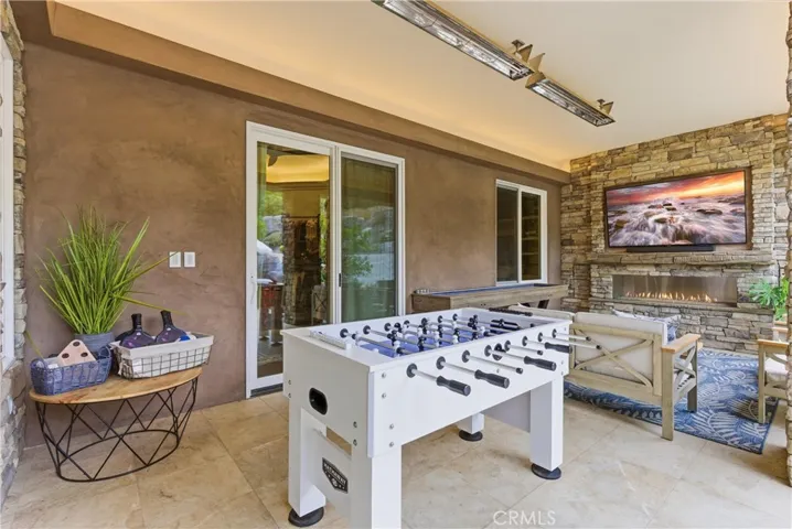 Outdoor lounge area with fireplace and TV entertainment wall