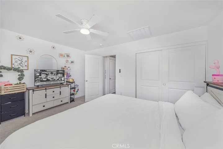 Spacious primary room uptairs with ceiling fan and plantation shutters.