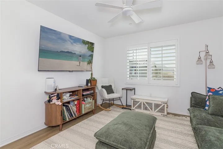 Great room with ceiling fan and plantation shutters.