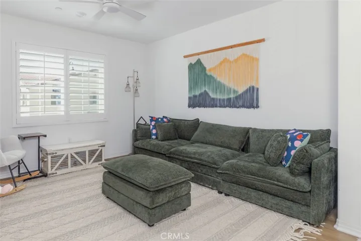 Great room with ceiling fan and plantation shutters.